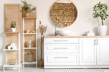 Interior of stylish bathroom with white counters, mirror and shelving unit