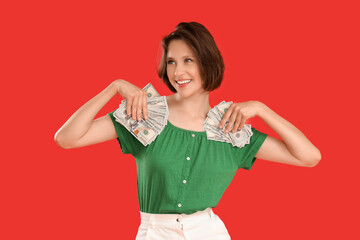 Pretty young woman with money on red background