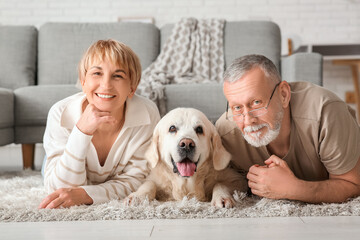 Mature couple with Labrador dog lying on floor at home