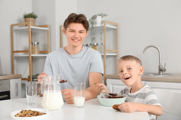 Happy father and his little son eating cornflakes with milk on breakfast at home