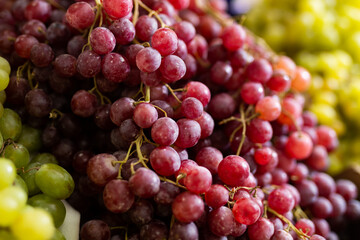 Close-up view of vines of red grapes on the stand in large open-air grocery store