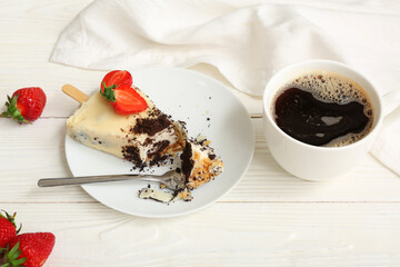 Plate with tasty cheesecake pop and cup of coffee on white wooden background