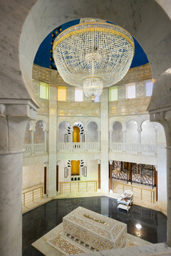 Central hall and interior of mausoleum of Habiba, Tunisia. Tomb of president is decorated with white marble, columns, and tiles. In center of first floor there is tomb and throne