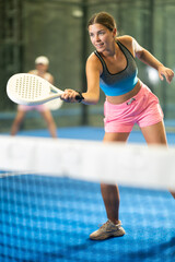 Portrait of cheerful girl paddle tennis player during friendly doubles couple match at court