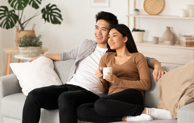 Obraz premium Home Weekend. Lovely filipino couple watching film resting on a couch at home, copy space