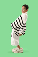 Fototapeta premium Little African-American boy in adult clothes on green background