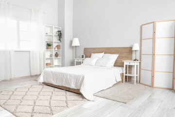 Interior of bedroom with bed, shelving unit and folding screen