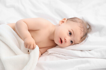 Cute little baby with towel lying on bed after bathing, closeup