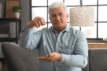 Male hypnotist with pendulum in office