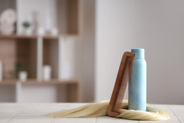 Naklejka premium Hair spray with strand and comb on table in beauty salon