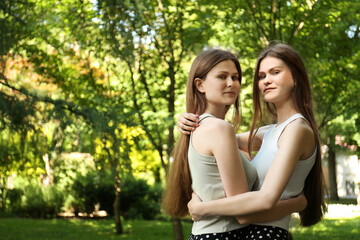 Naklejka premium Portrait of two beautiful twin sisters in park, space for text