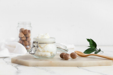 Glass jar with shea butter and nuts on light table