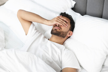 Morning of man suffering from headache in bed