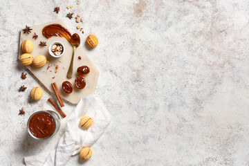 Board with tasty walnut shaped cookies, boiled condensed milk and ingredients on white grunge table