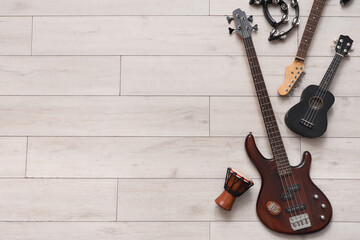 Different guitars, drum and tambourine on wooden background