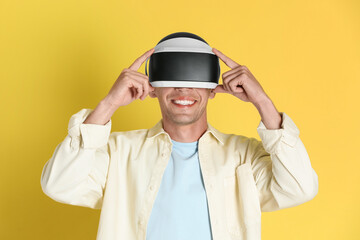 Smiling man using virtual reality headset on yellow background