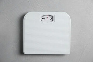 One bathroom scale on grey textured background, top view