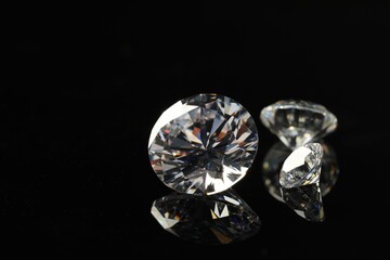Beautiful shiny diamonds on black mirror surface, closeup. Space for text