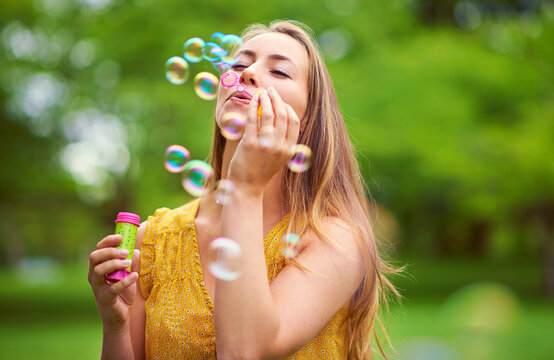 Nature, fun and woman blowing bubbles in outdoor park for happiness, holiday or summer vacation. Relax, game and female person with soap toy for excitement, joyful or celebration in garden on weekend