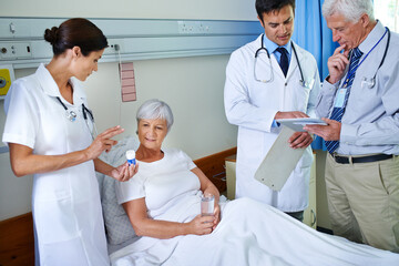 Hospital, pills and doctors with old woman, explaining or communication for health of patient or medical. Clinic, wellness and nurse with senior person, water or medicine in appointment of healthcare