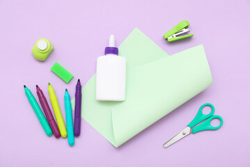 Bottle of glue, scissors and felt-tip pens on lilac background. Top view