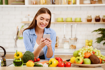 Young Woman Texting when Cooking Healthy Food In Kitchen, Copy Space