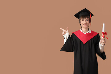 Male graduating student with  diploma pointing at something on beige background