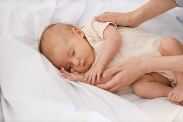 Mother with her sleeping little baby on bed, closeup