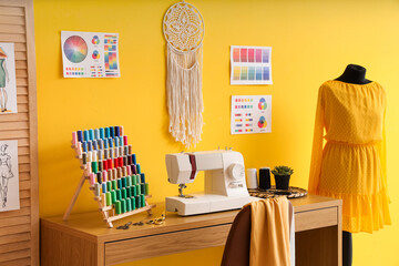Tailor's workplace with sewing machine, thread spools and color palettes in atelier