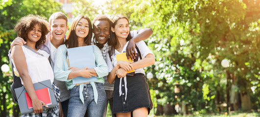 Portrait of happy multicultural students posing outdoors while walking together in park, free space
