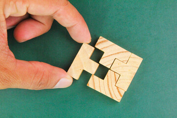 hands complete a wooden puzzle. last missing piece, solutions and challenges concept  