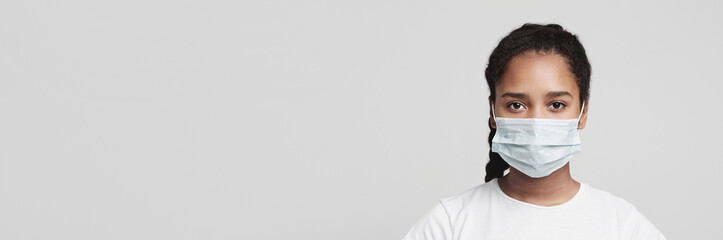 Flu concept. Teen african girl with protective face mask, grey studio background