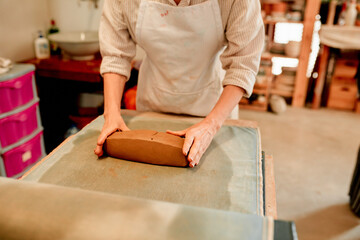 Potter, hands and clay on table in workshop for handmade craft and production process for ceramics. Pottery manufacturing, entrepreneur and small business for creative design and artistic sculpture