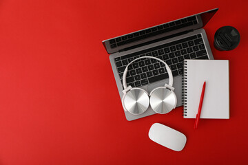 A cup of coffee with headphones and a laptop on a red background