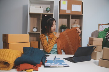 vlogger, blogger small SME business asian beautiful woman using mobile phone video call for sell clothes live stream selling online, show product present detail at home office, entrepreneur ecommerce