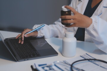 Doctor holding medicine bottle and taking notes in office.