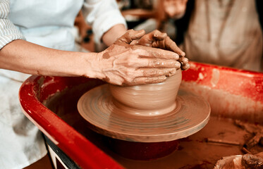 Hands, pottery wheel and woman with artistic expression, clay and creativity in workshop or tools. Closeup, ceramic or person with equipment, productivity or talent with hobby, mold or small business