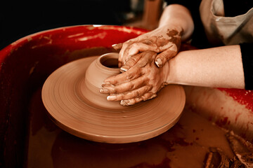 Hands, pottery wheel and woman with clay, craft and creativity in workshop, hobby and artistic. Closeup, entrepreneur and person with equipment, designer and tools with small business and industry