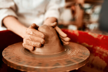 Hands, pottery wheel and process in workshop for sculpture, art and development for startup. Clay, artistic person and career or talent in small business for project or design for retail in gallery