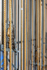 Vertical Image.  Theater stage rigging with theatrical equipment, lighting, supports, and chains. Photo taken from an elevated position looking across the rigging.	