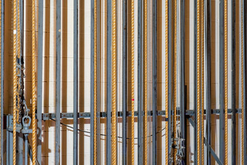 Theater stage rigging with theatrical equipment, lighting, supports, and chains. Photo taken from an elevated position looking across the rigging.	