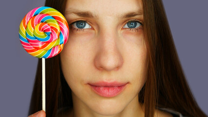 A portrait of a cute girl with a colorful lollipop in her hand