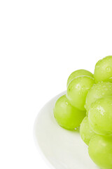 Fresh Shine Muscat on a white plate. Close-up, white background - vitis vinifera 'shine muscat'