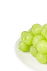 Fresh Shine Muscat on a white plate. Close-up, white background - vitis vinifera 'shine muscat'