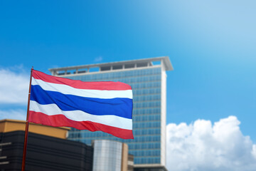 A Thailand flag with the colors red, white, and blue is flying