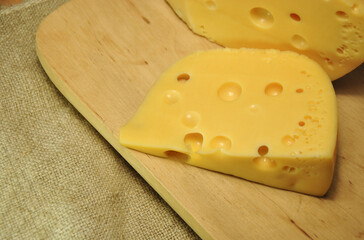 cheese on wooden board. piece of cheese on a wooden cutting board. dark photo