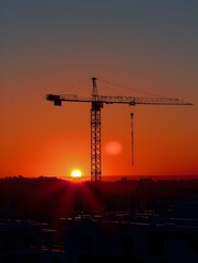 Silhouetted Crane Against Dramatic Sunset Sky Over Urban Landscape