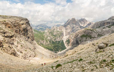 Awesome landscape, Italian Dolomites. 2 people descending a hiking trail from Büllelejochhütte, rifugio pian de cengia. Majestic landscape, Active summer vacation. Healhty lifestyle. Amazing nature.