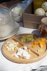Top view of small snack in the park. Different types of cheese is on the wooden serving board.