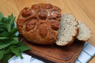 Top view of Baked homemade round bread cut in slices with nettles on wooden table with fresh nettle plants